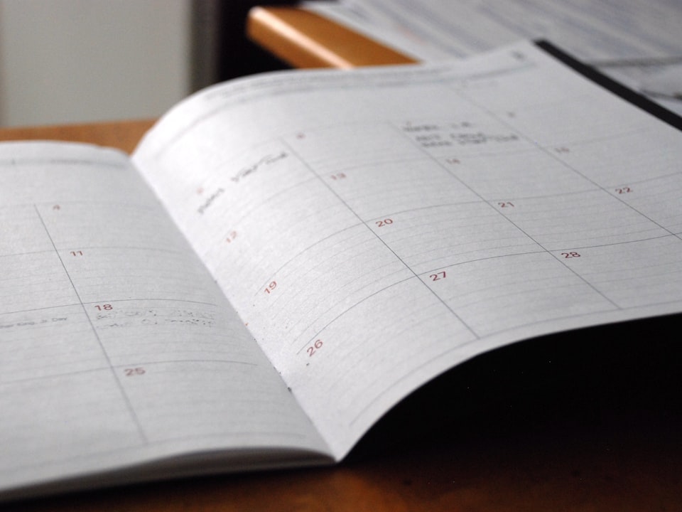 An open monthly planner on a wooden desk