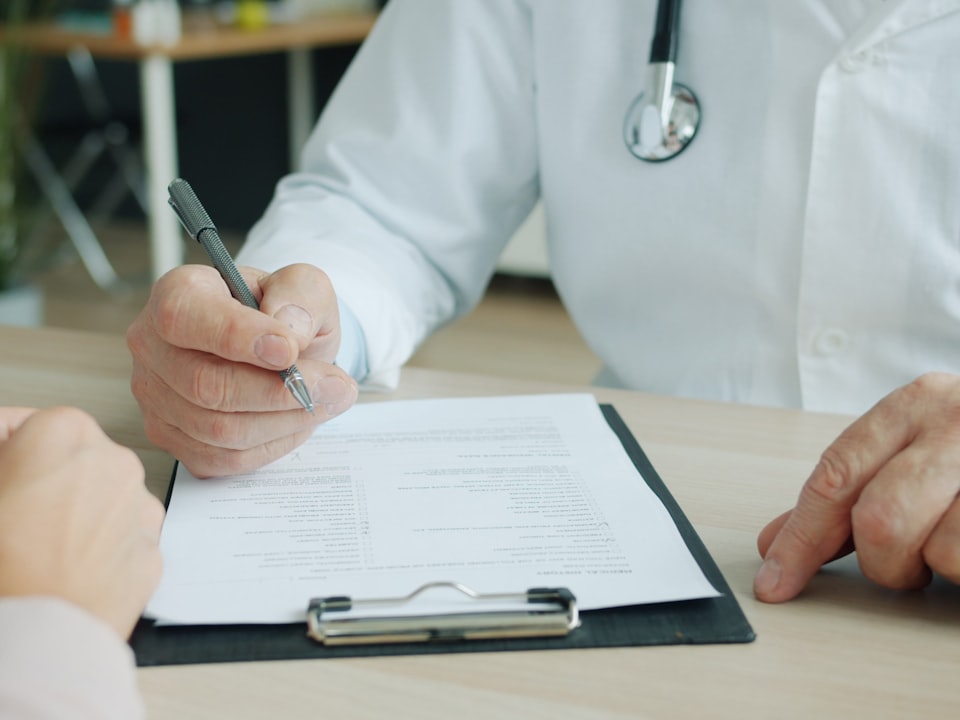 A doctor writing on a patient's chart